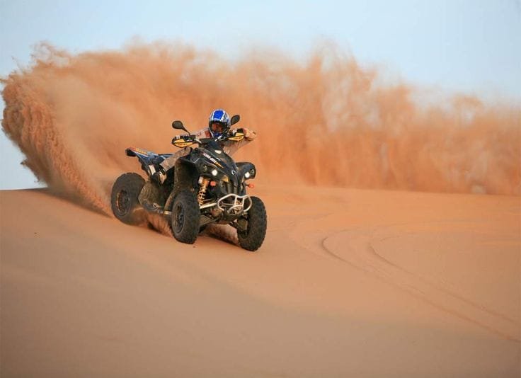 Quad bike throwing sand on a dune near Dubai