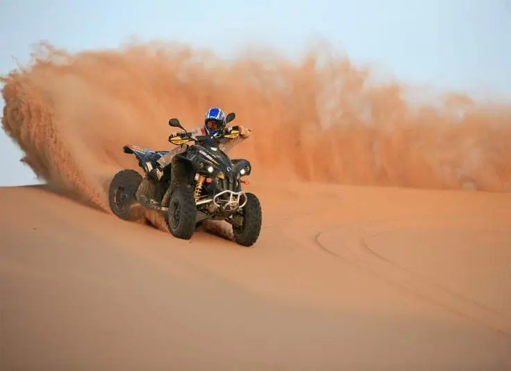Quad bike throwing sand on a dune near Dubai