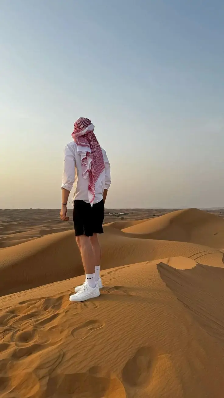 Visitor sitting on the steep sand slope of a giant dune in the Liwa desert Abu Dhabi