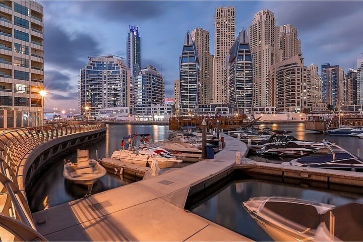 Dubai Marina at dusk with yachts moored along the boardwalk, a stop on the Dubai city tour