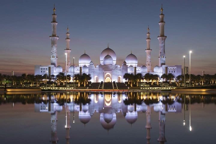 Sheikh Zayed Grand Mosque at dusk with its domes reflected in the pools, the first stop on our Abu Dhabi city tour